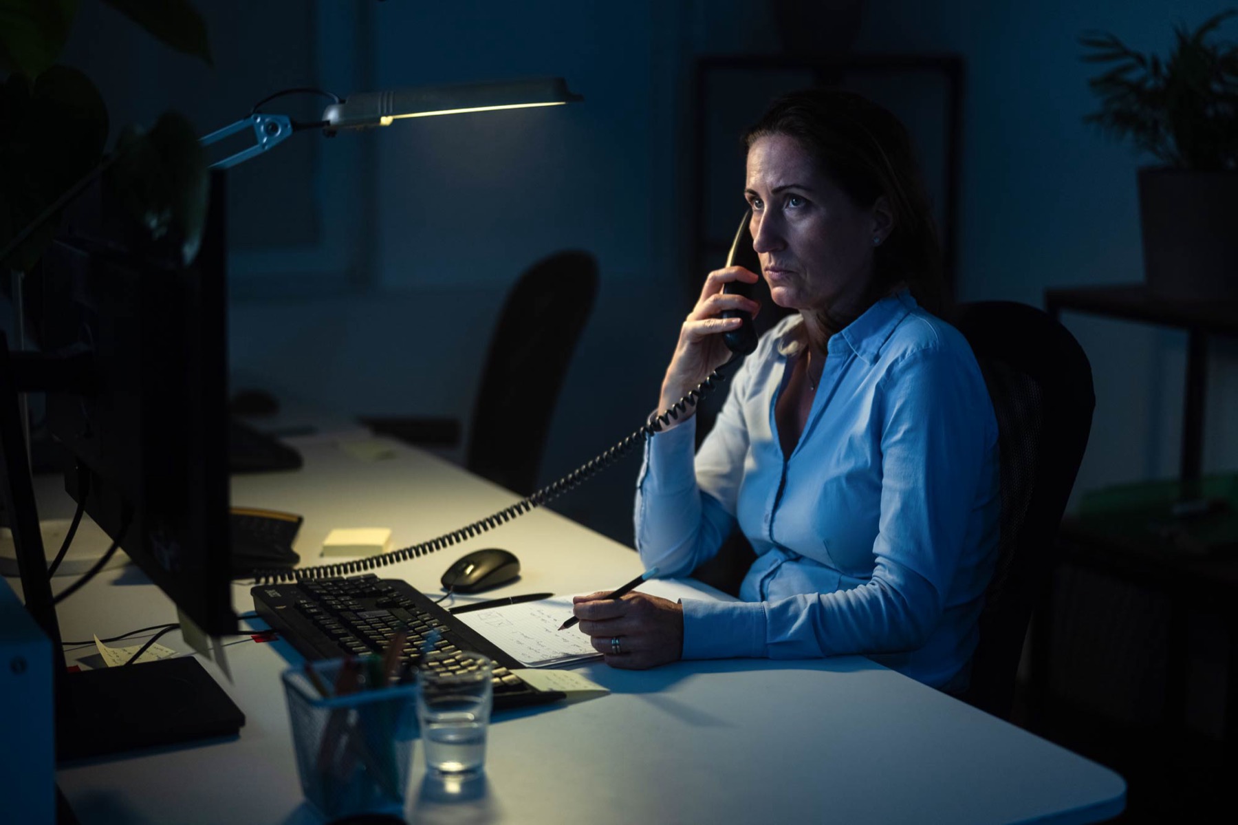 Mitarbeiterin telefoniert abends am Schreibtisch, Unternehmensreportage in Wien