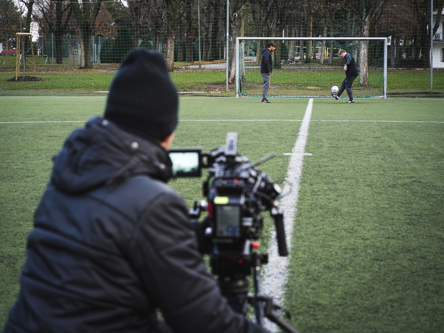 Kameramann filmt zwei Darsteller am Tor eines Fußballplatzes