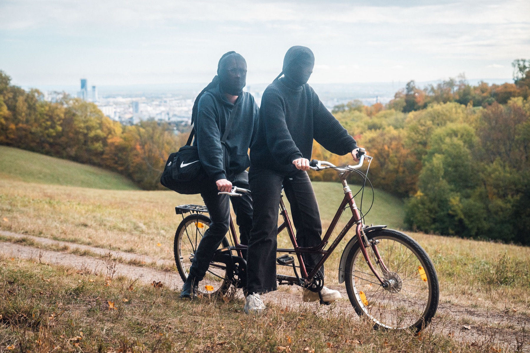 Zwei maskierte Darsteller mit Tandem vor dem Wiener Stadtpanorama
